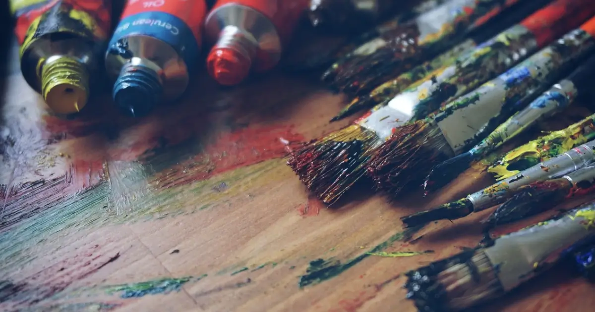 Rembrandt with Rocks Rock Painting at the Idea Forge paint brushes and paint tubes on a wooden surface